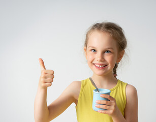 Adorable smiling little girl with a delicious dessert in hand looking at camera showing thumb up. Facial expression, children, summer time, healthy food. Close up studio portrait isolated on white