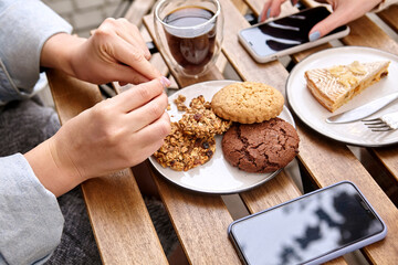 sweet dessert with a cup of coffee and female hands with a phone