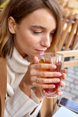 woman drinks hot tea in the autumn on the street