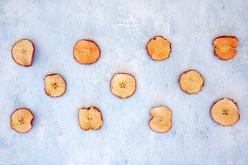 Obraz na płótnie Canvas Arrangement of dried apple and dried orange slices on blue background