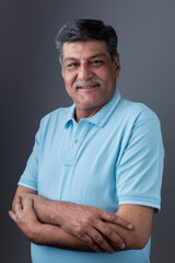 Studio portrait of a confident mature man posing against a gray background.