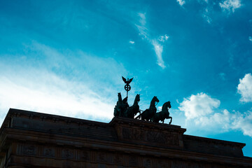 Brandenburger Tor (Brandenburg Gate), in shadow on blue sky with clouds, famous landmark in Berlin, Germany.