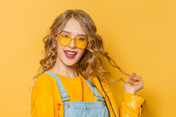 Beautiful woman with long curly hair smiling on yellow background
