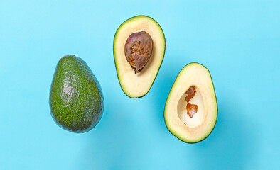 Fresh avocado halves with seed flying on blue background. Minimal concept organic summer food. Flat...
