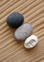 Fototapeta na wymiar Zen garden stones. Three rounded pebbles on lined sand.