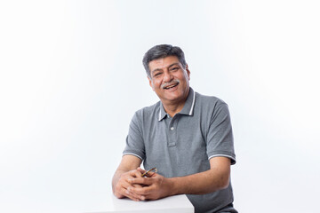 Studio portrait of a confident mature man posing against a gray background.