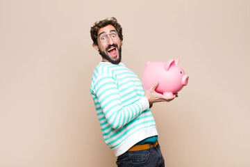 young cool man holding a piggy bank against clean wall