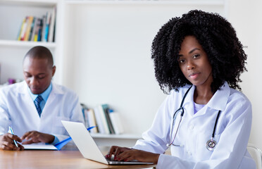 African american medical student working at computer with male scientist