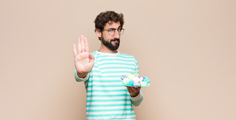 young man with macaroons against flat wall