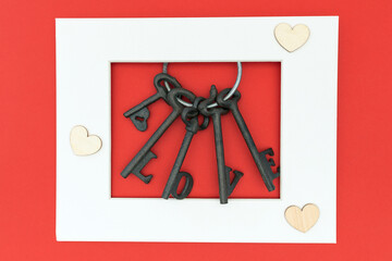 A set of love keys on red background with wooden hearts and copyspace/space for text