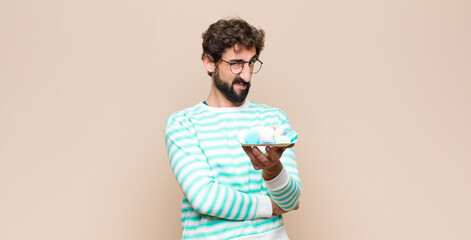 young man with macaroons against flat wall