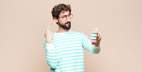 young man with macaroons against flat wall