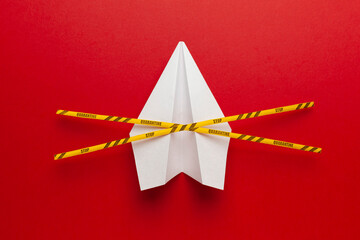 Paper airplane on red background under quarantine. Cancellation of flights of civil and touristic aviation. Crisis of air travel.
