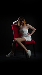 woman in white dress on red chair