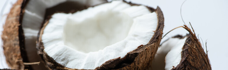 close up view of tasty coconut halves on white background, panoramic shot