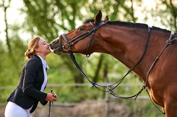 Rolgordijnen Horse rider girl and horse on a farm. horse kisses a girl. © Rakursstudio