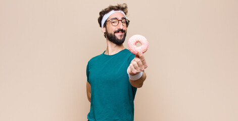 young sports man having a snack holding a pink sugar donut