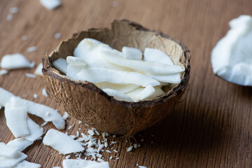 selective focus of fresh tasty coconut flakes in shell on wooden table