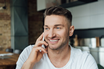 Smiling man talking on smartphone in living room