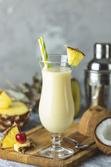 Glass of tasty Frozen Pina Colada Traditional Caribbean cocktail decorated by slice of pineapple, served on light wooden cutting board