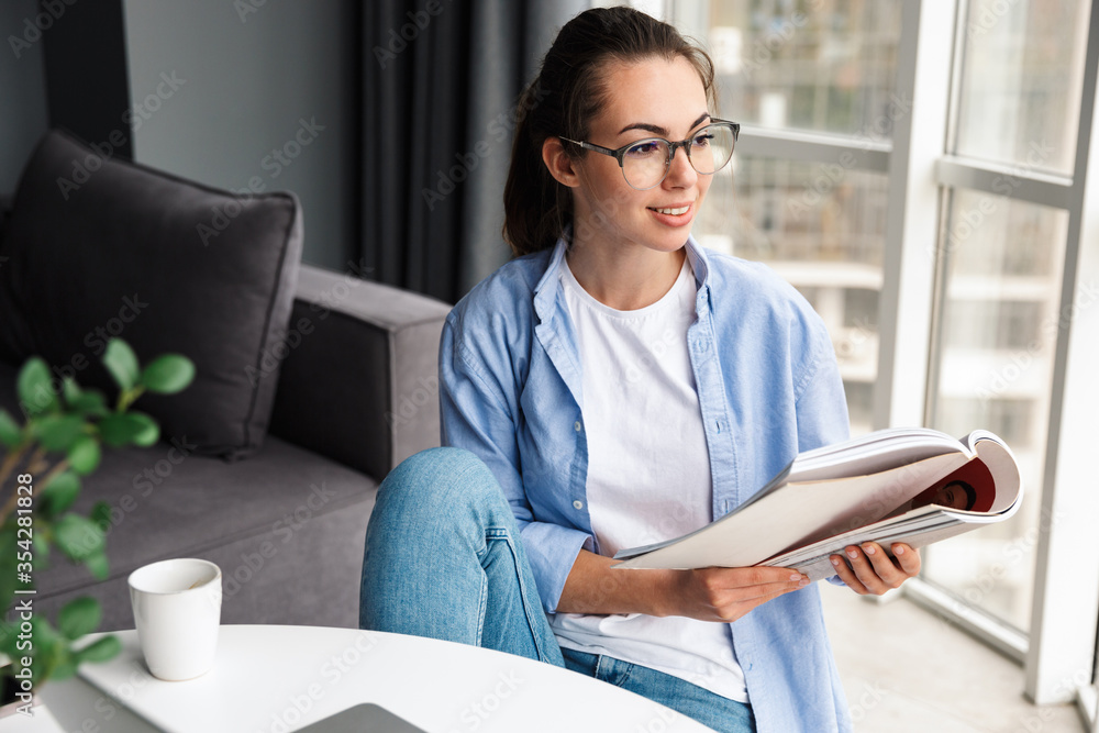 Sticker Image of woman reading book and working with laptop while sitting