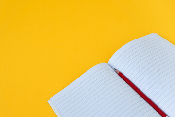 Back to school Education concept Close up open composition book and red pencil on yellow background...