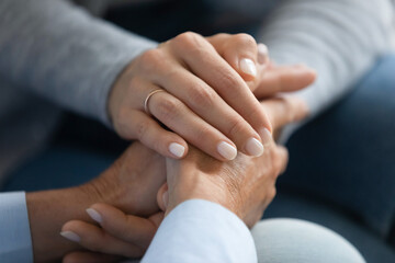 Close up adult daughter holding mothers hand, gesture symbol of psychological support in difficult...