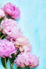 Pink peonies bouquet closeup, spring flowers for Mother's Day on ligh blue wooden background. Wedding events and other holidays.