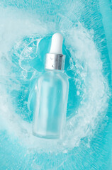 Skincare serum essence glass bottle with water drops in ice blue background, vertical. Concept...