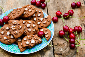   Cherries and cocoa cookies with  vanilla star decoration on wooden background. Summer dessert