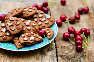   Cherries and cocoa cookies with  vanilla star decoration on wooden background. Summer dessert
