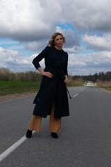 Blond woman walks by parapet of road on sunny day.