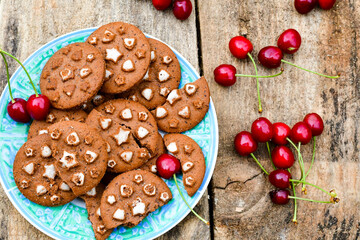   Cherries and cocoa cookies with  vanilla star decoration on wooden background. Summer dessert