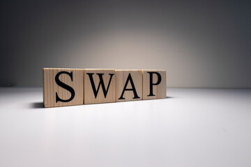 The word swap was written with wooden cubes. Close-up of spot lights and on a white table. Close up.