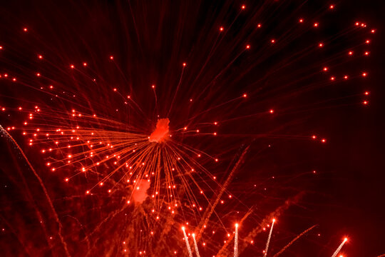 Salute. Bright, red splashes of fireworks in the dark sky. Night fireworks.