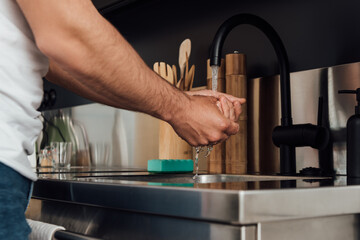 cropped view of man standing and washing hands