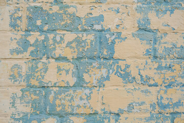Blue Old colorful paint with cracks on yellow brick wall