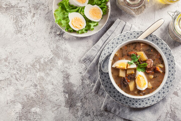 The sour soup made of rye flour with mushrooms served with eggs