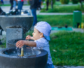 little boy playing with water in the park