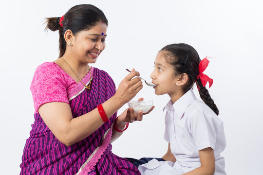 Mother feeding her daughter with curd before going to school