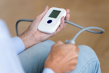 Elderly woman monitoring controlling arterial blood pressure using sphygmomanometer device close up view. Heart cardiovascular chronic diseases, attack prevention of older people, health care concept