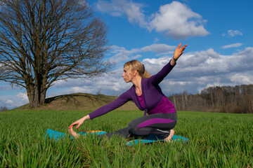 A middle-aged blonde woman practices yoga in nature. Healthy lifestyle. Body concentration.