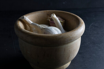 wooden bowl with garlic heads on a black background