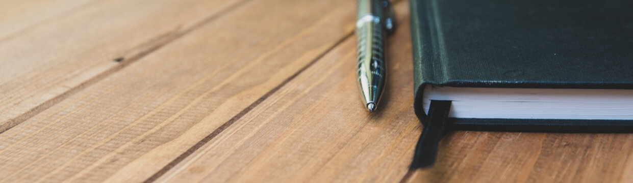 panoramic view of a notebook and pen on a light wooden background. Education concept