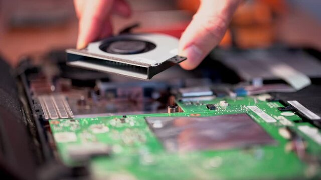 A computer technician inserted a clean new cooler to cool the processor in a laptop computer. Close-up.