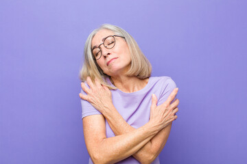 senior or middle age pretty woman feeling in love, smiling, cuddling and hugging self, staying...