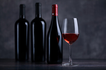 The red wine in the glass, along with a bottle of wine made from red grapes, is laid on a wooden floor and a beautiful backdrop. Ready for partying