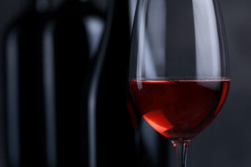 The red wine in the glass, along with a bottle of wine made from red grapes, is laid on a wooden floor and a beautiful backdrop. Ready for partying
