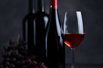 The red wine in the glass, along with a bottle of wine made from red grapes, is laid on a wooden floor and a beautiful backdrop. Ready for partying