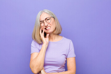 senior or middle age pretty woman holding cheek and suffering painful toothache, feeling ill,...